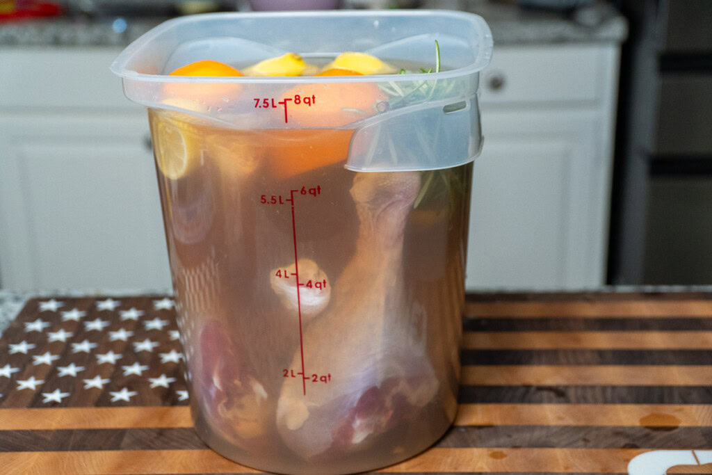 a big tub of brine with raw turkey legs in it