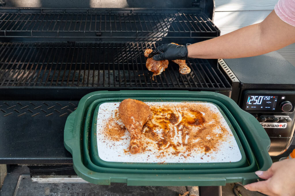 raw seasoned turkey legs being placed in the smoker