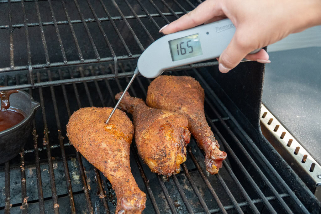 an instant read thermometer inserted into a turkey leg reading 165F