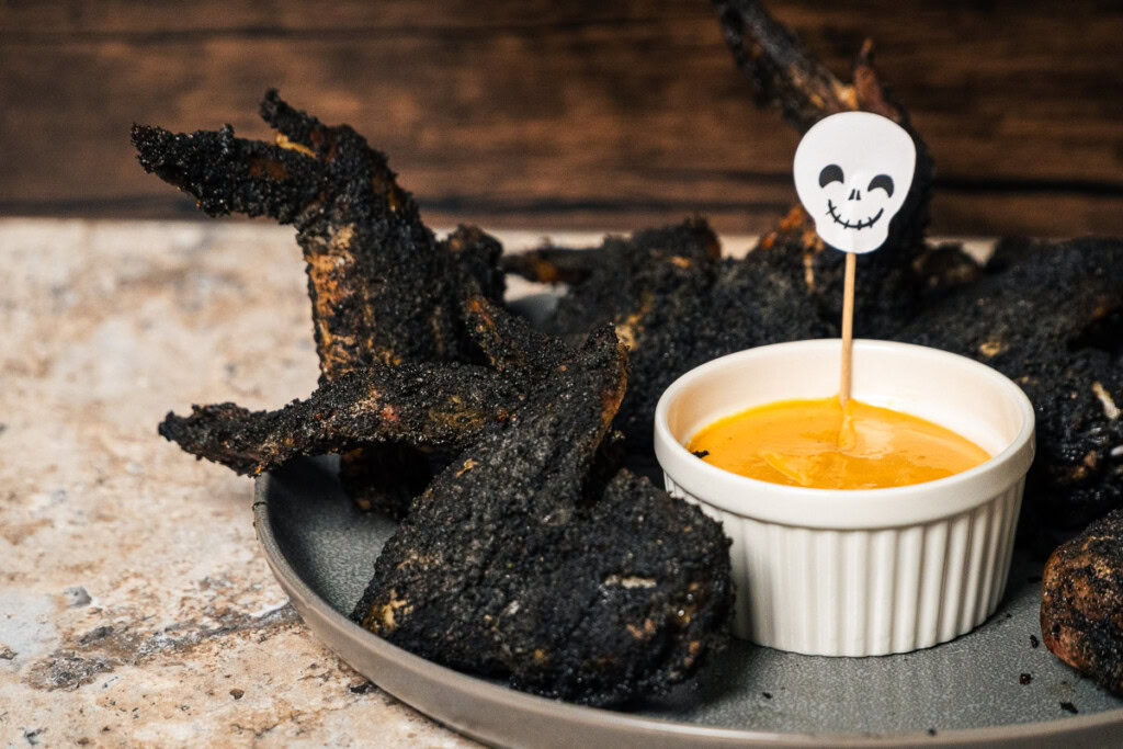smoked bat wings on a plate with a bowl of spicy ranch beside them