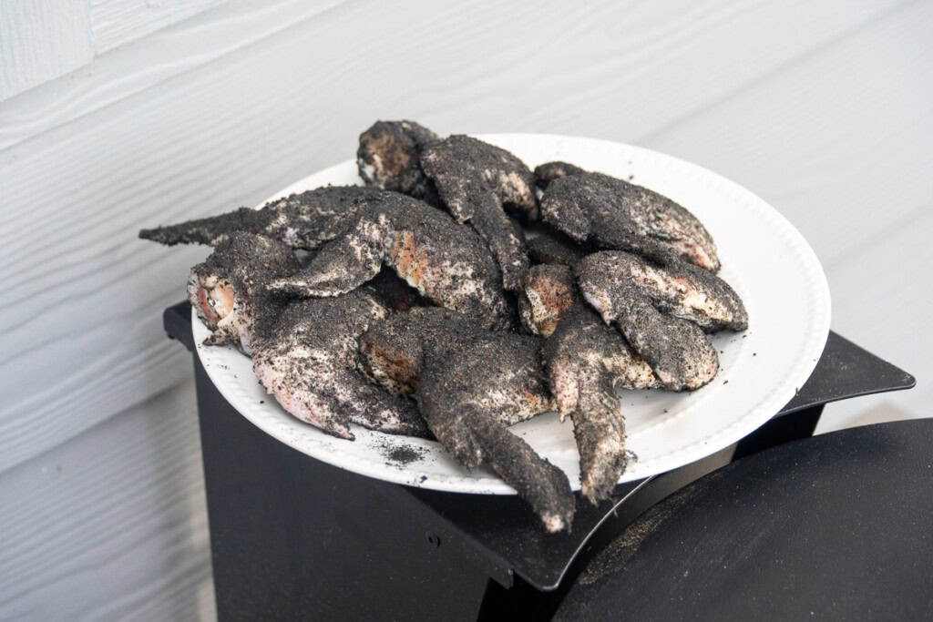 a white plate with raw seasoned chicken  bat wings