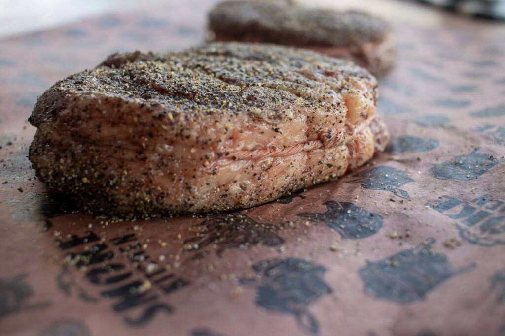 a side on shot of a raw seasoned chuck eye steak