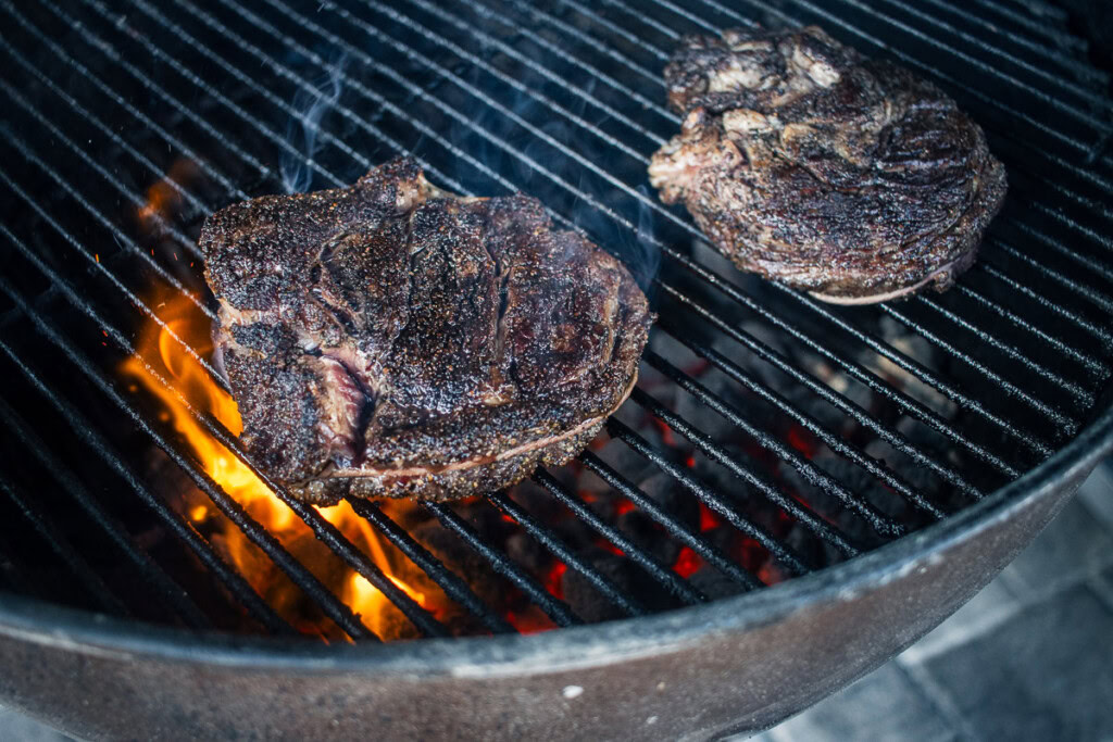 chuck eye steak cooking on a charcoal grill