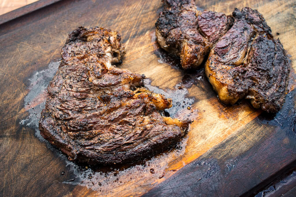 cooked chuck eye steak resting on a wooden board after grilling