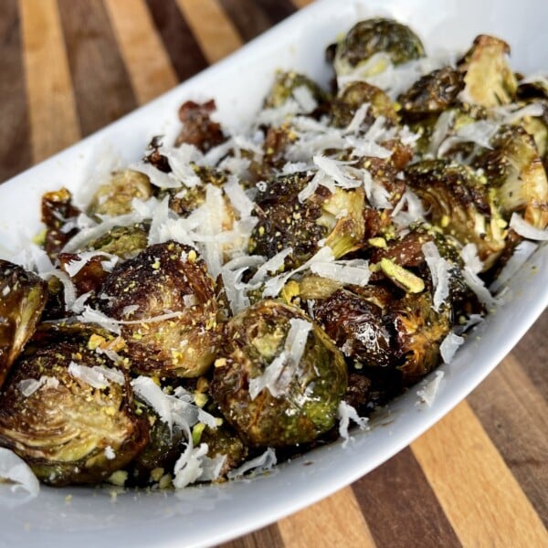 airfryed brussel sprouts plated in a deep white bowl with shredded cheese.