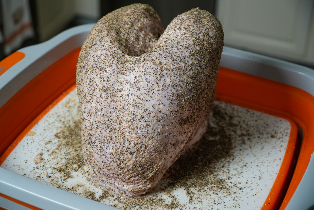 a raw seasoned turkey breast on a white board