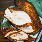 Smoked turkey breast sliced on a plate showing peppery bark and juicy white meat for a pellet grill recipe.