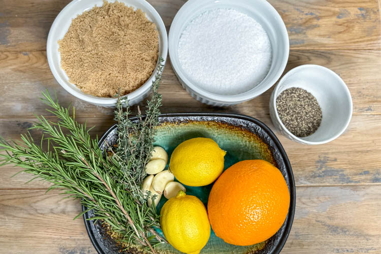bowl of brown sugar, bowl of salt, bowl of black pepper, herbs, garlic, lemons orange