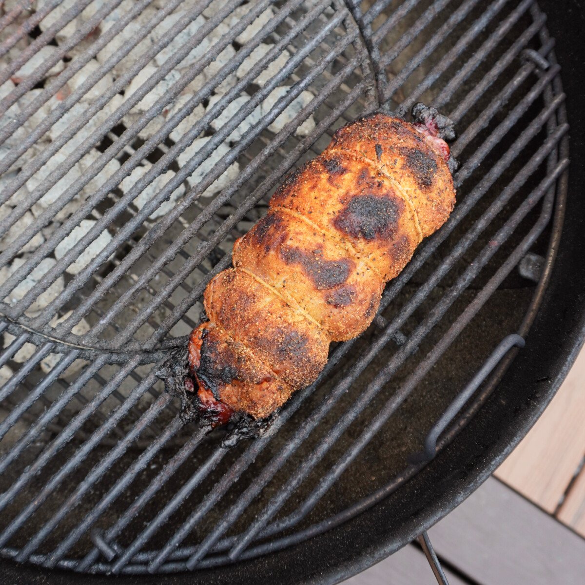 turkey roll cooking on charcoal grill.