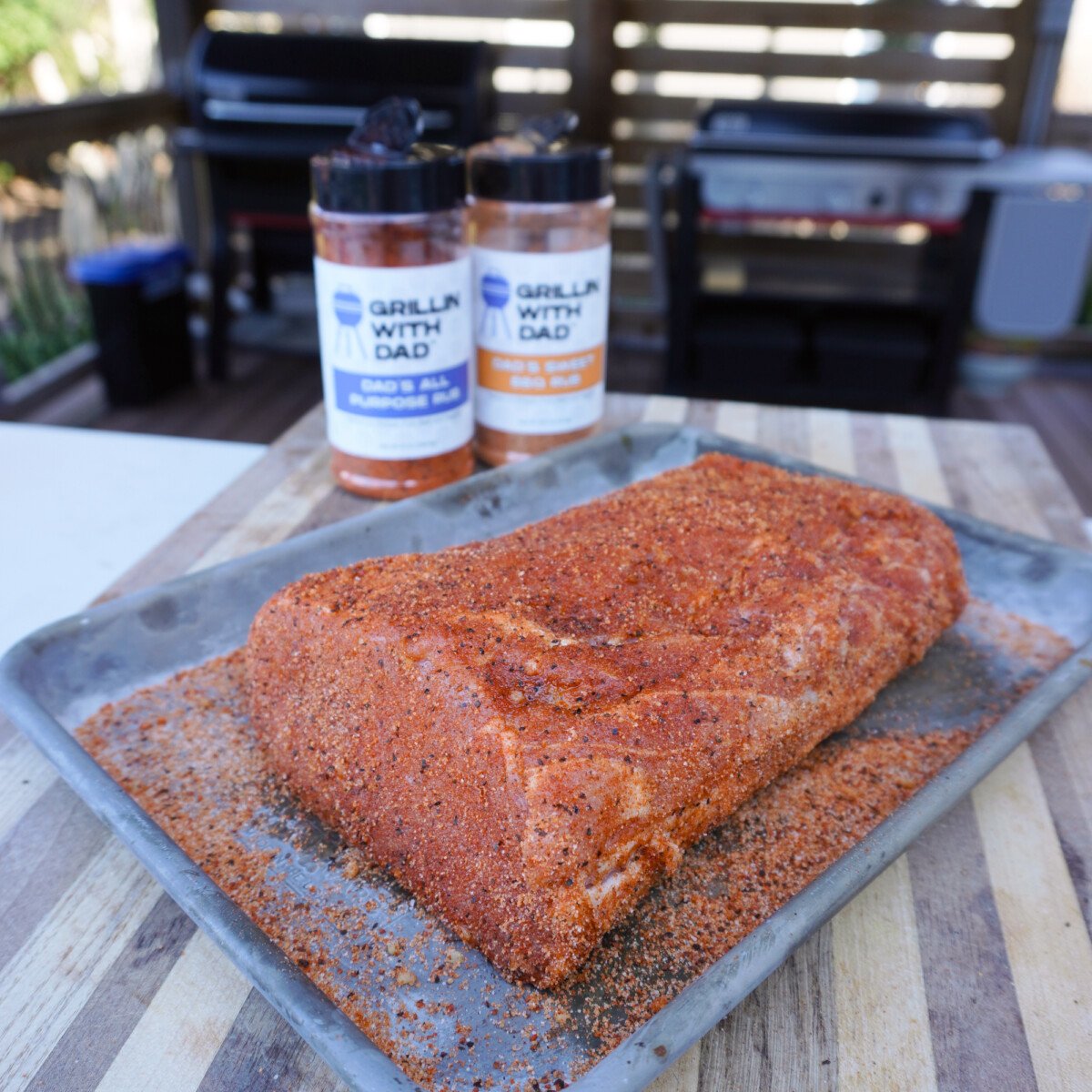seasoned pork on a tray with seasoning bottles in the background.