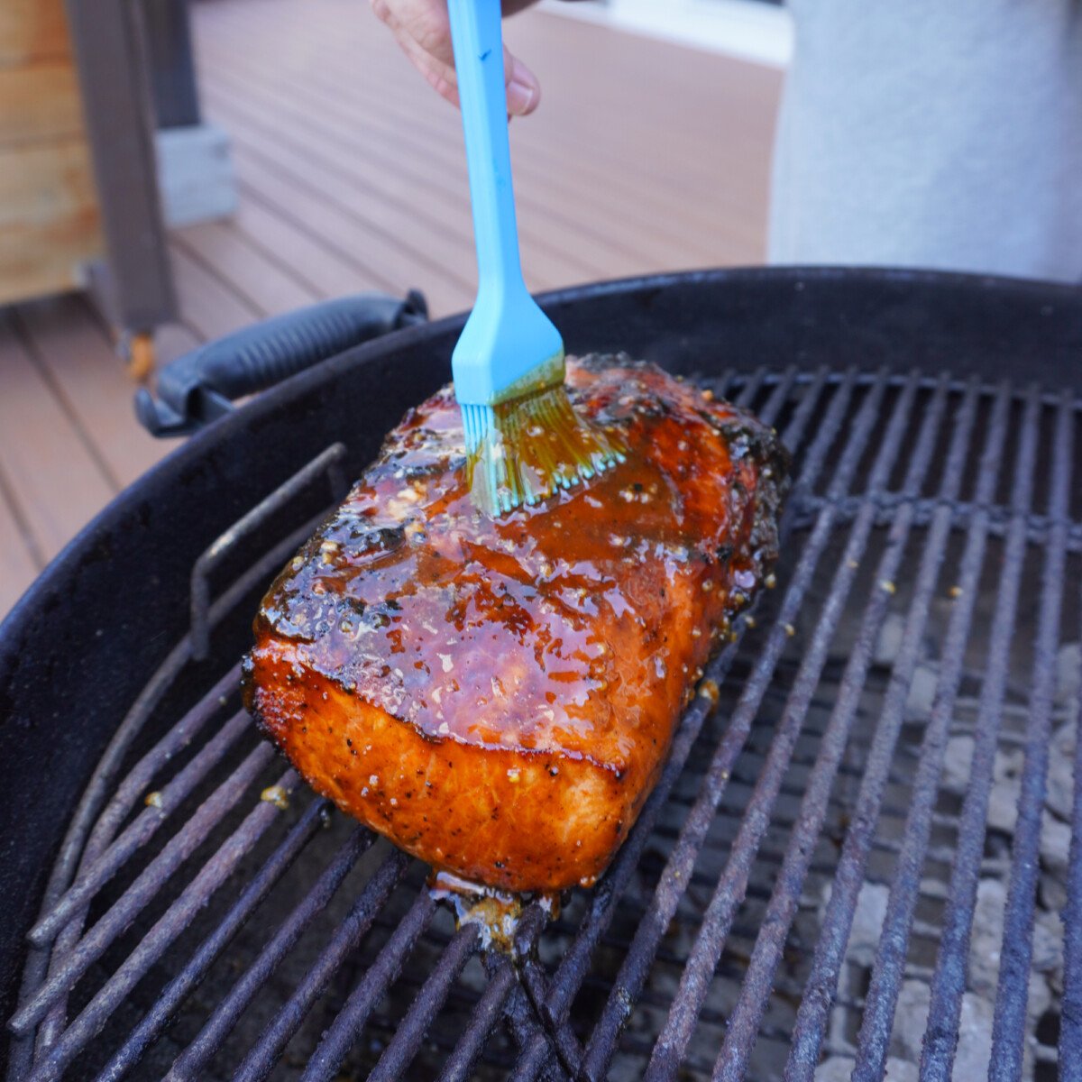 brushing apple cider glaze over the grilled pork roast.