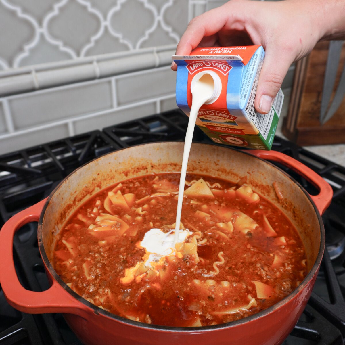 adding heavy cream into the lasagna soup.
