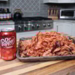 shredded ham with cherry dr. pepper sauce on tray with a can of cherry dr. pepper on the side and kitchen in the background.