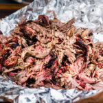 Close up of shredded smoked lamb shoulder showing juicy texture and smoky crust