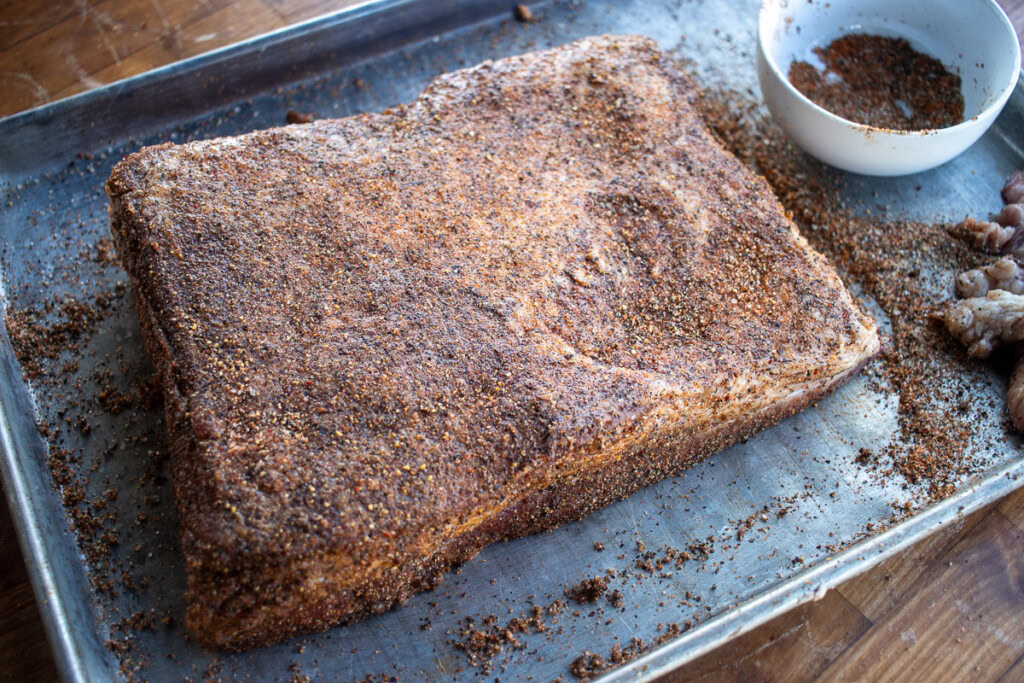 a raw seasoned piece of beef belly on a metal tray