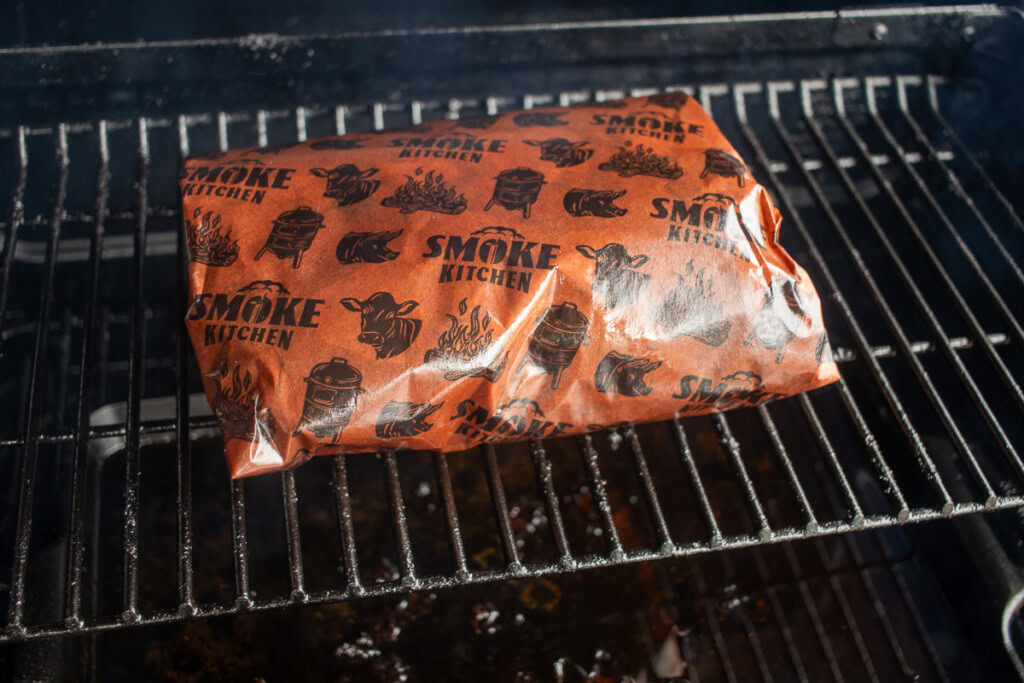smoked beef belly wrapped in butcher paper in the smoker braising