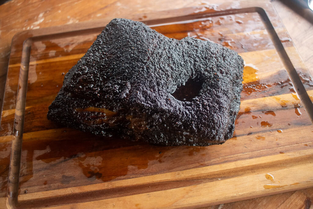 a smoked piece of beef belly resting on a wooden board