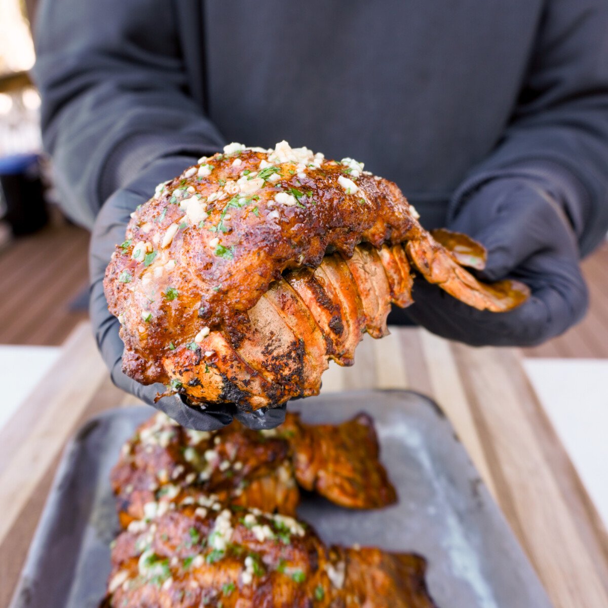 smoked cajun lobster tail presented in hands.