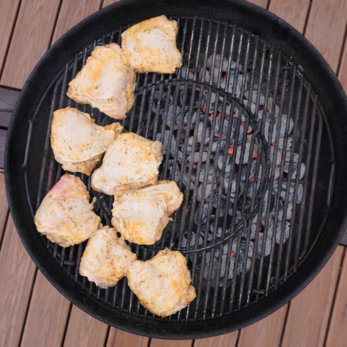 marinated chicken thighs on the indirect side of a charcoal grill.