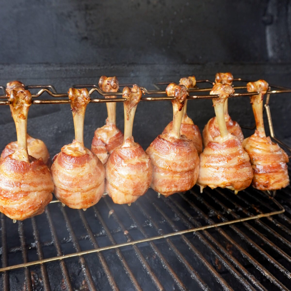 grilled bacon wrapped chicken drumsticks on the smoker.
