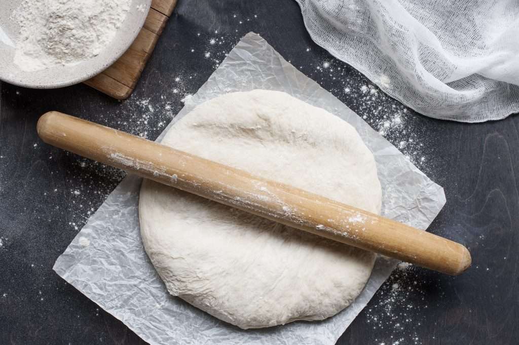 Pizza Dough on Parchment with rolling pin