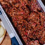 Smoked pulled beef made from chuck roast in a foil pan, shredded and sauced, ready for sandwiches