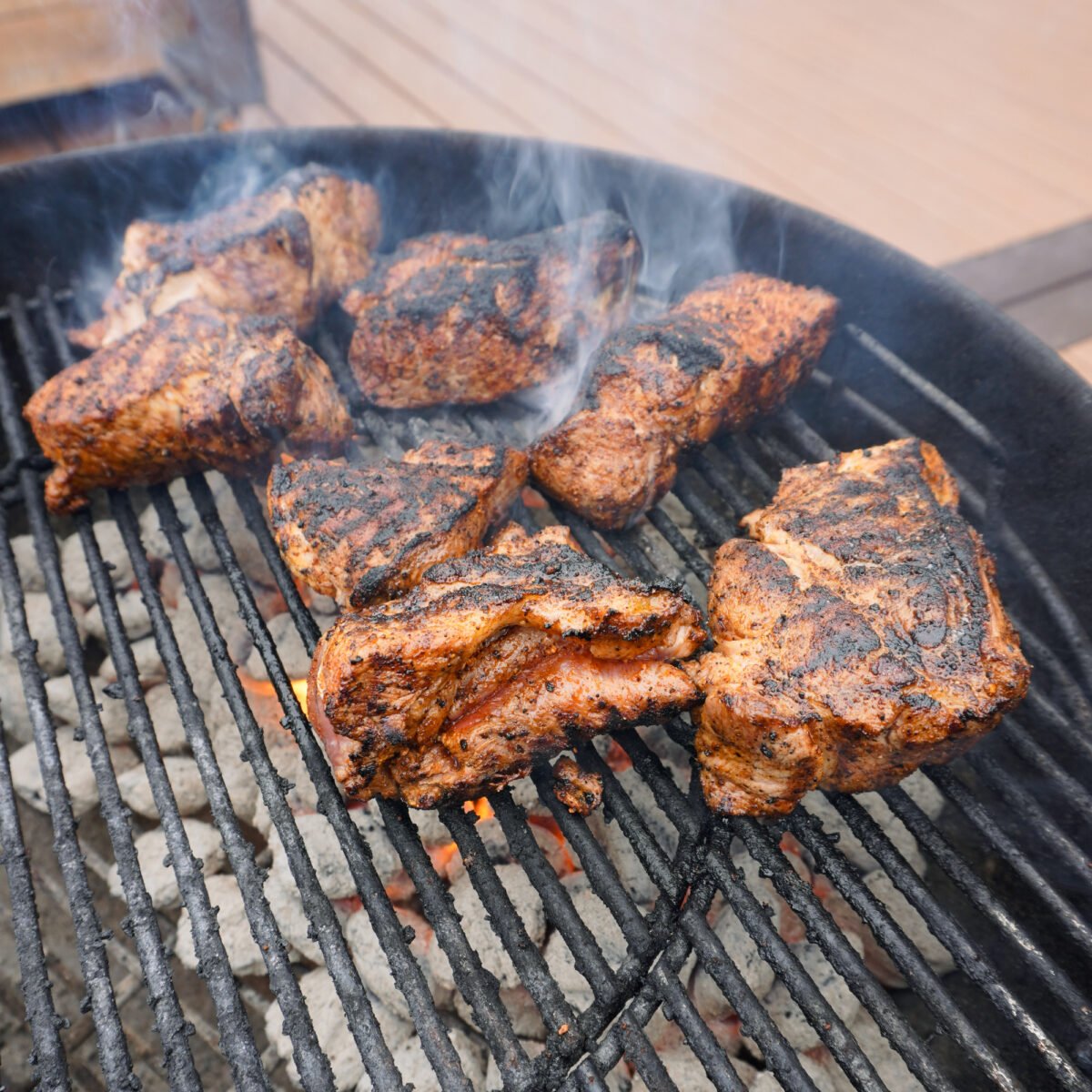 seared pork pieces on charcoal grill.