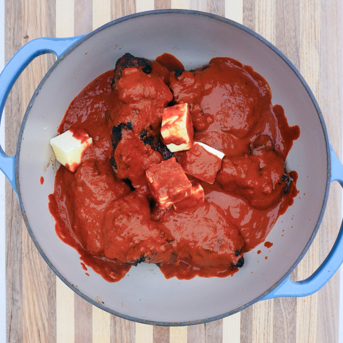 seared pork shoulder chunks covered in an adobo sauce in a dutch oven.