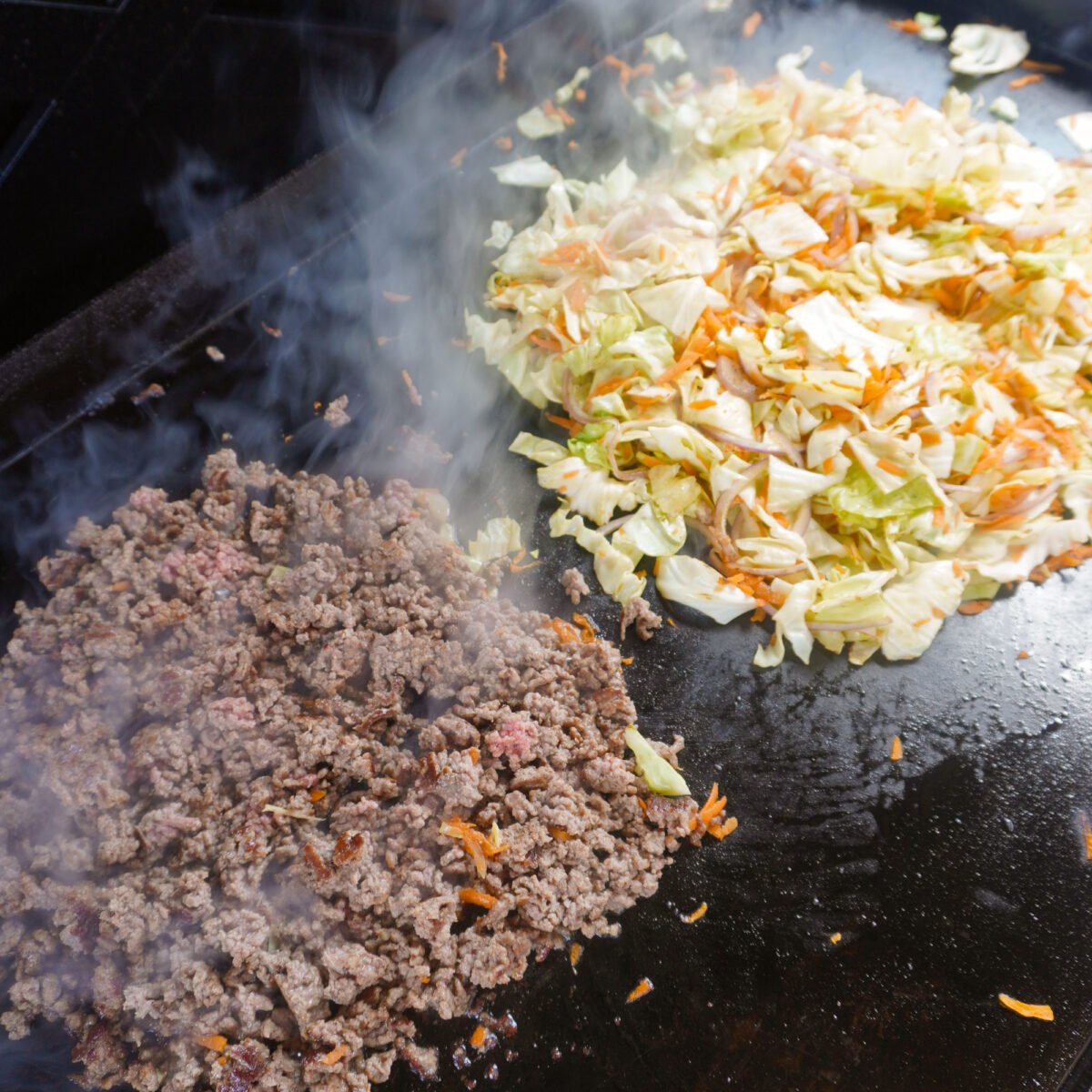 cooked ground beef and veggies on griddle.