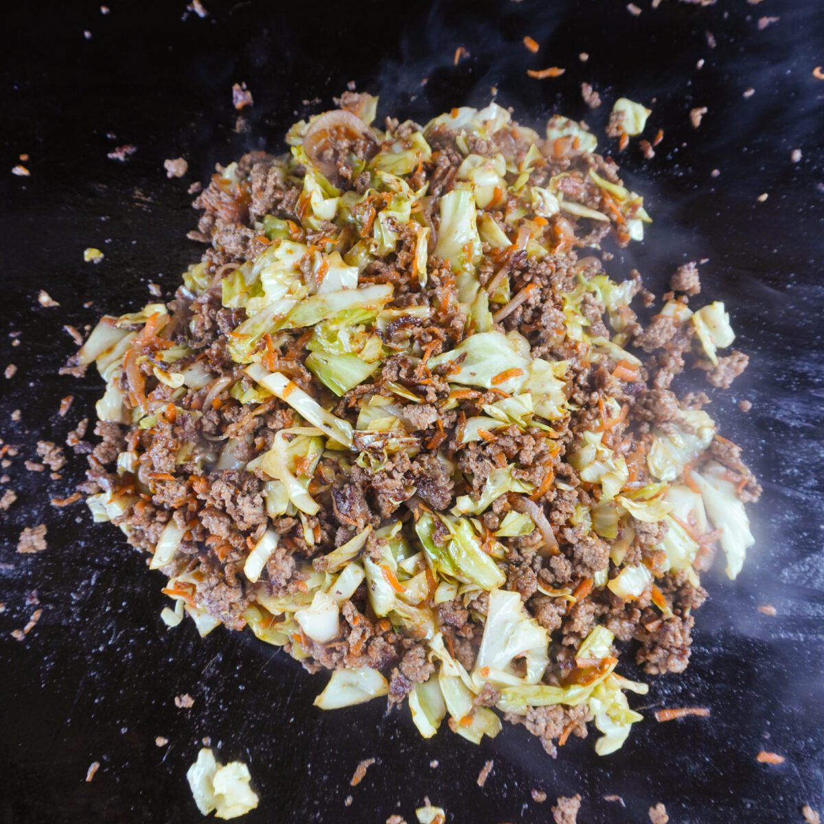 beef egg roll bowl ingredients mixed together on griddle.