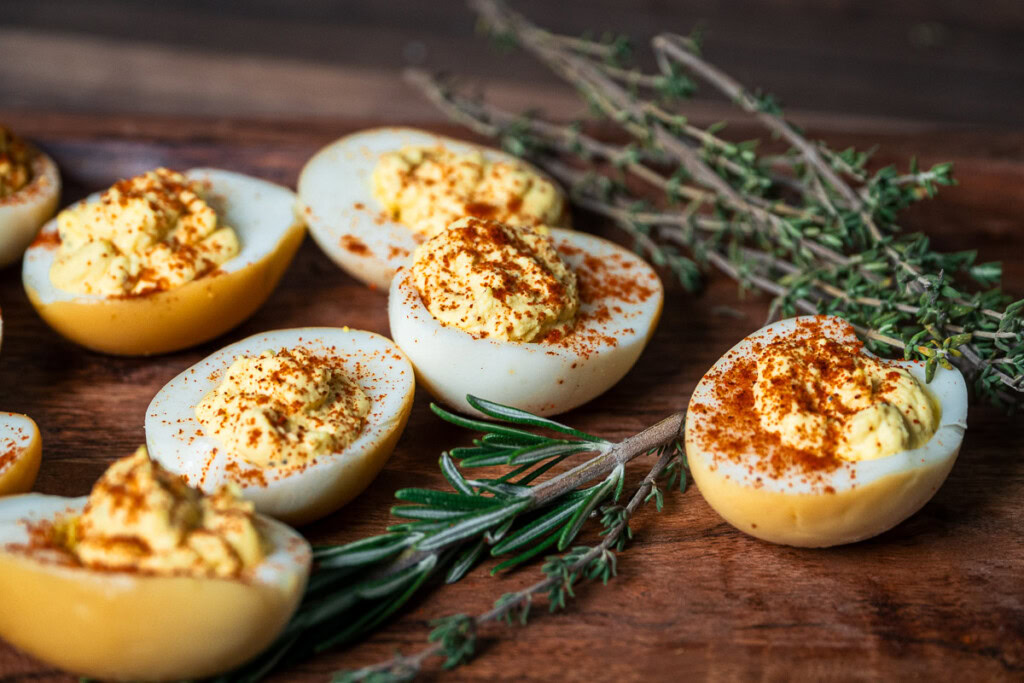 a wooden board with smoked deviled eggs and rosemary