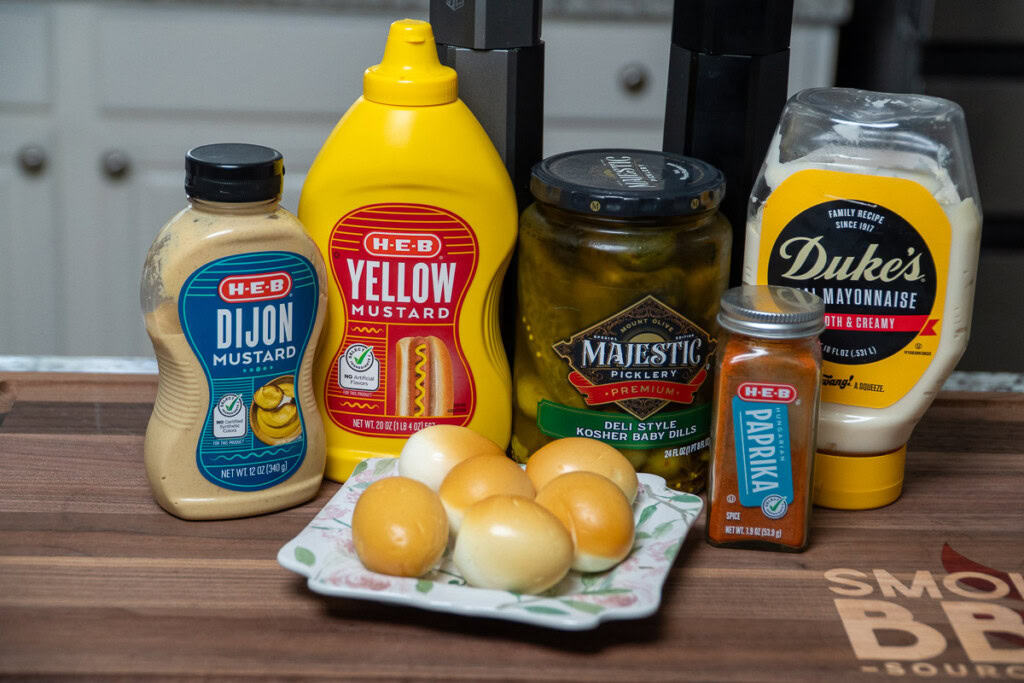 the ingredients for the smoked deviled eggs laid out on a wooden board