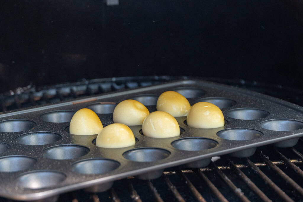 brown tinged boiled eggs in a muffin tray in the grilla grills smoker