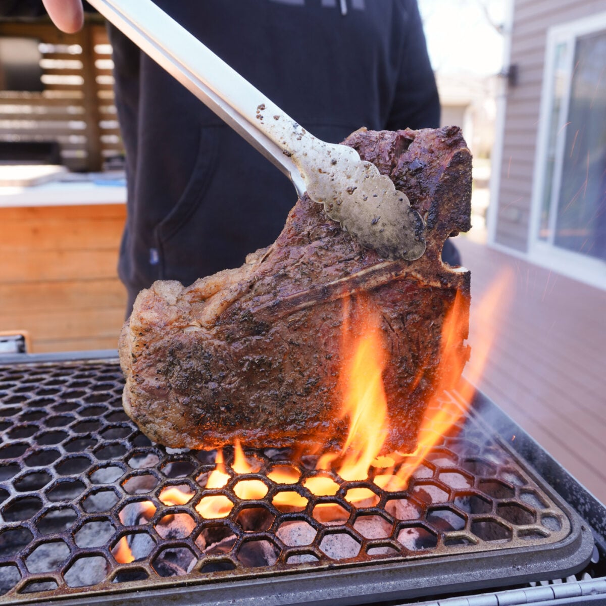 Grilled Porterhouse steak on the direct side of the grill being seared.