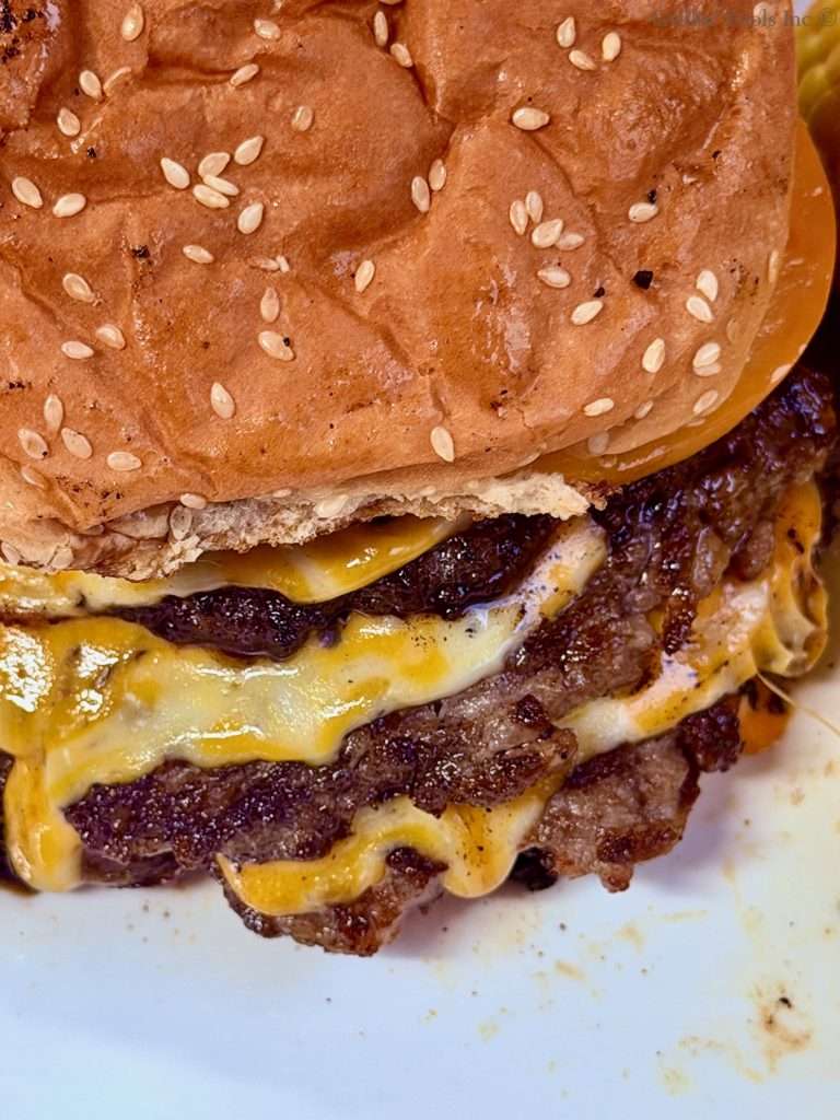 A close up of one of our triple decker ground pork smash burgers
