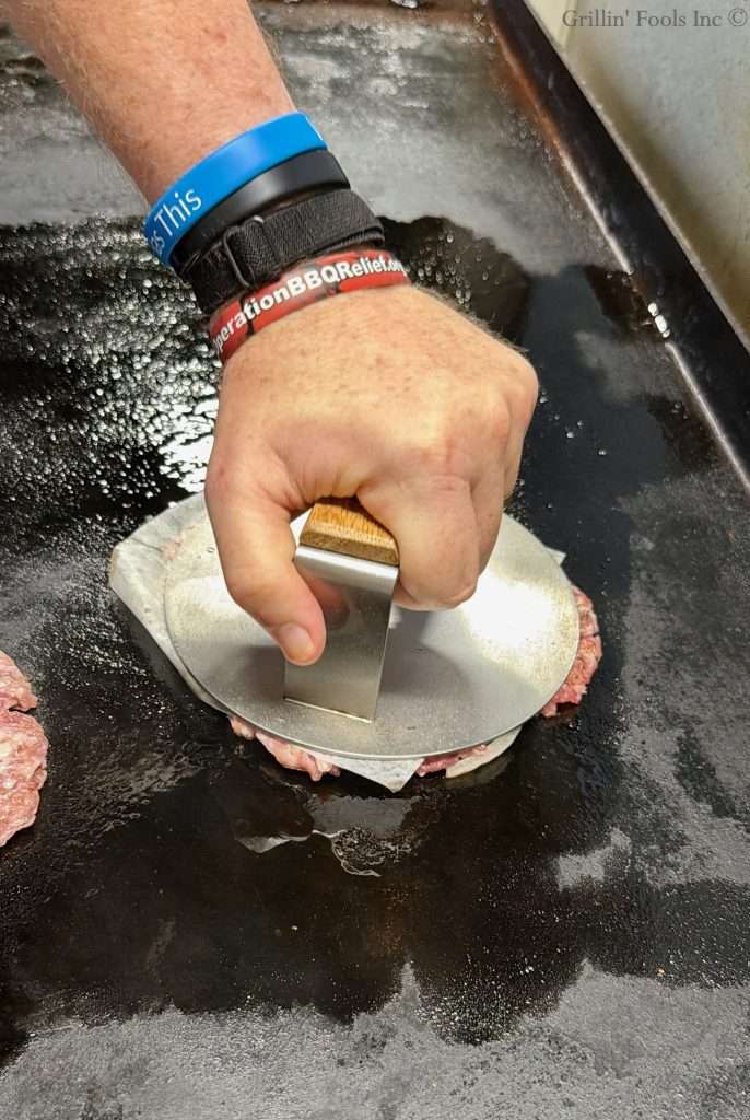 Smashing ground pork with a patty smasher