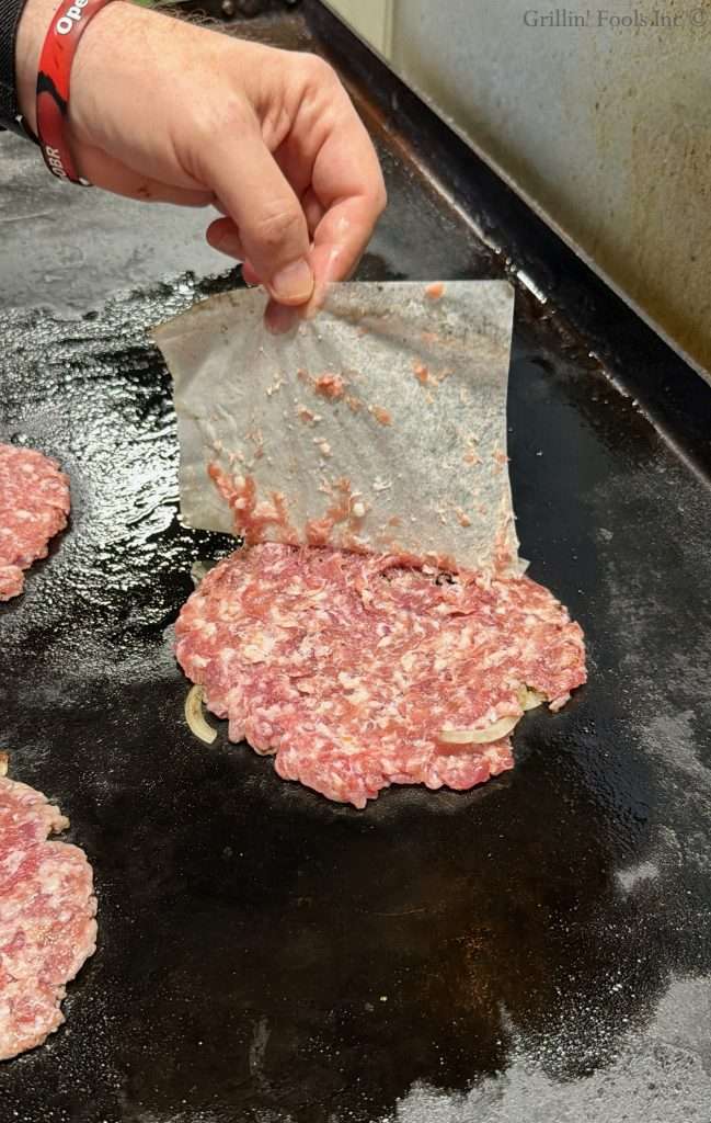 Pealing the patty paper back from a ground pork burger patty