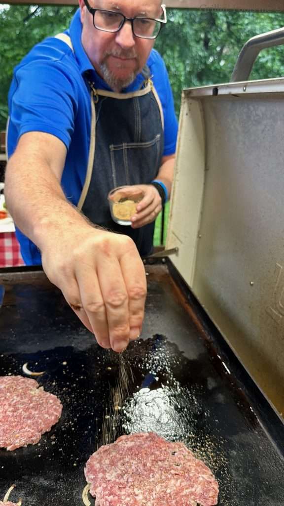 Seasoning ground pork smash burgers with salt, pepper, garlic
