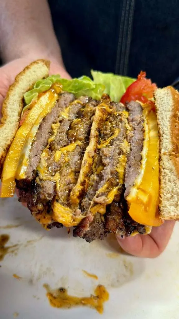 A cross section of a triple decker, ground pork smash burger sliced in half