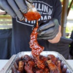 Smoked Sweet and Spicy Party Ribs with extra sauce being poured over.