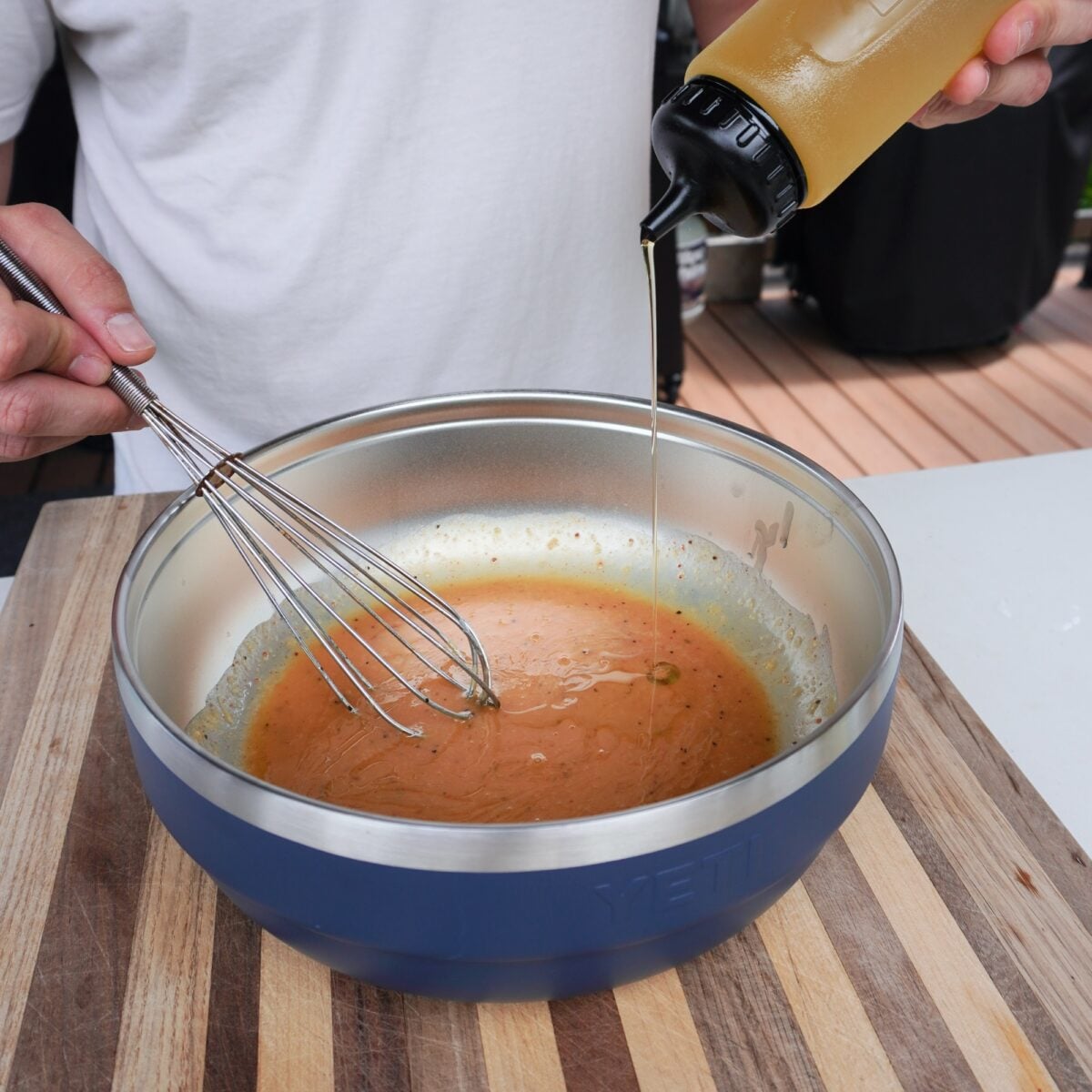 Olive oil being added and whisked to a chicken marinade.