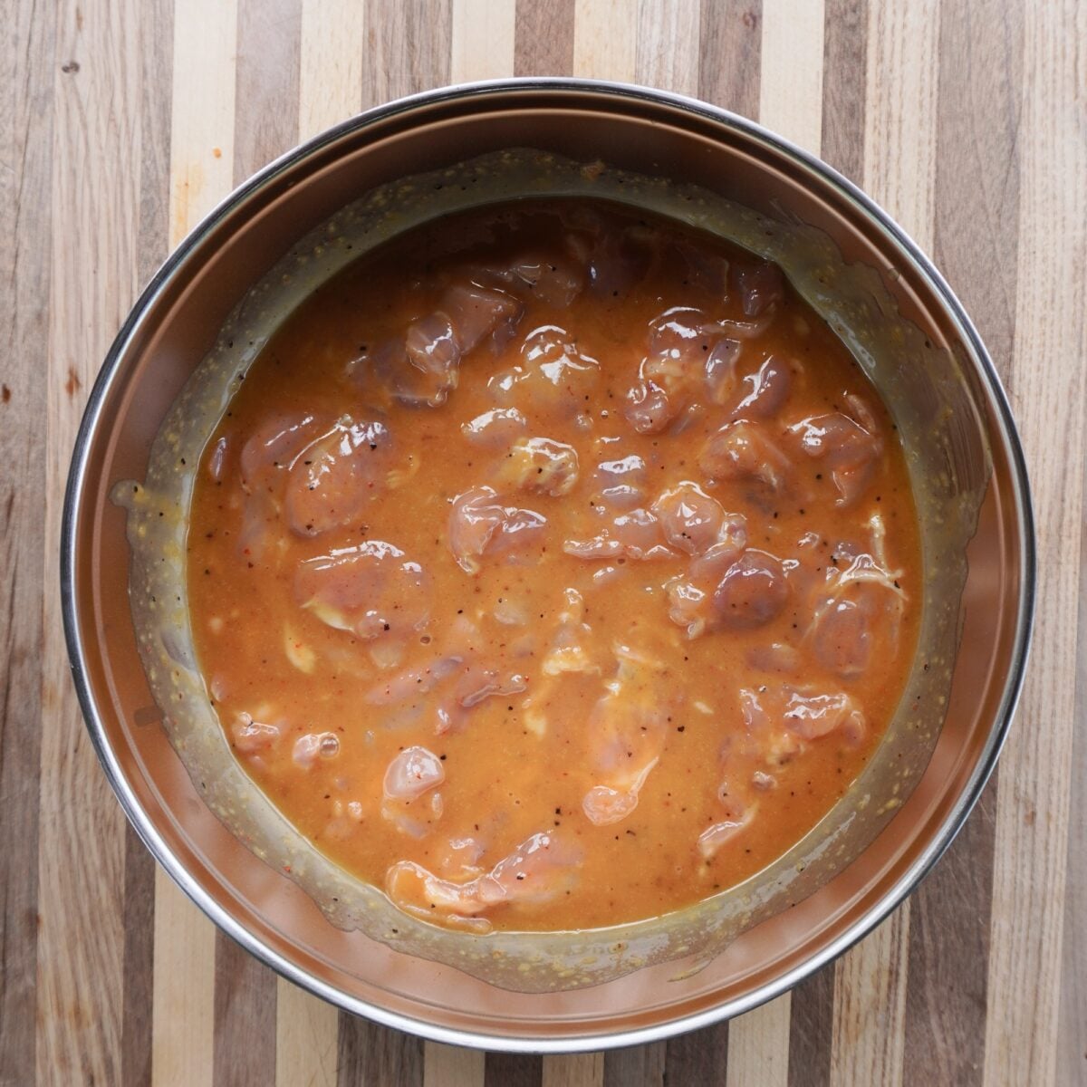 raw chicken thighs in a marinate in a large bowl.