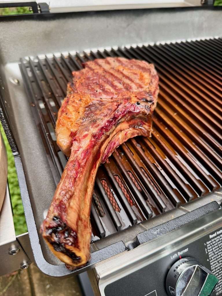 A charred tomahawk on a MHP hybrid grill over the sear station