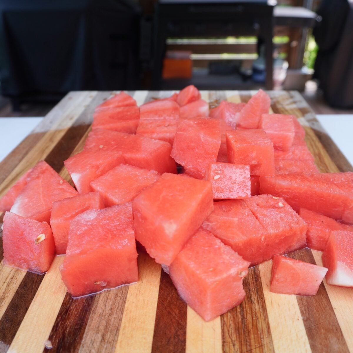 cubed up watermelon on wooden cutting board.