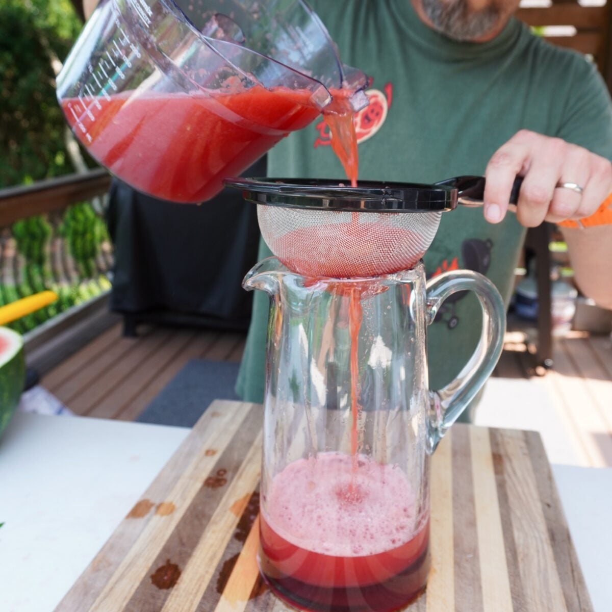 draining watermelon juice through drainer into a pitcher.