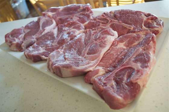 A platter covered with six, one inch thick, bone in pork steaks