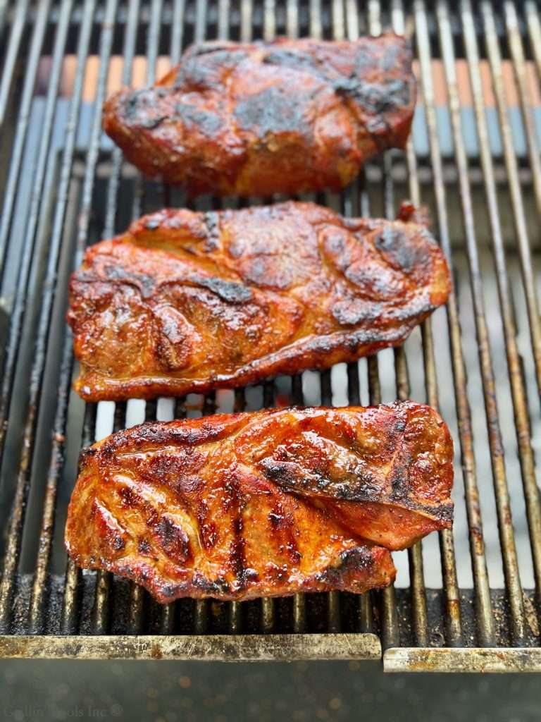 Barbecue pork steak grilling on a Santa Maria grill with caramelized glaze and charred edges