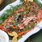 Lemon and Dill Smoked salmon on a platter, next to a bowl of creamy dill sauce, garnished with fresh dill and lemon slices
