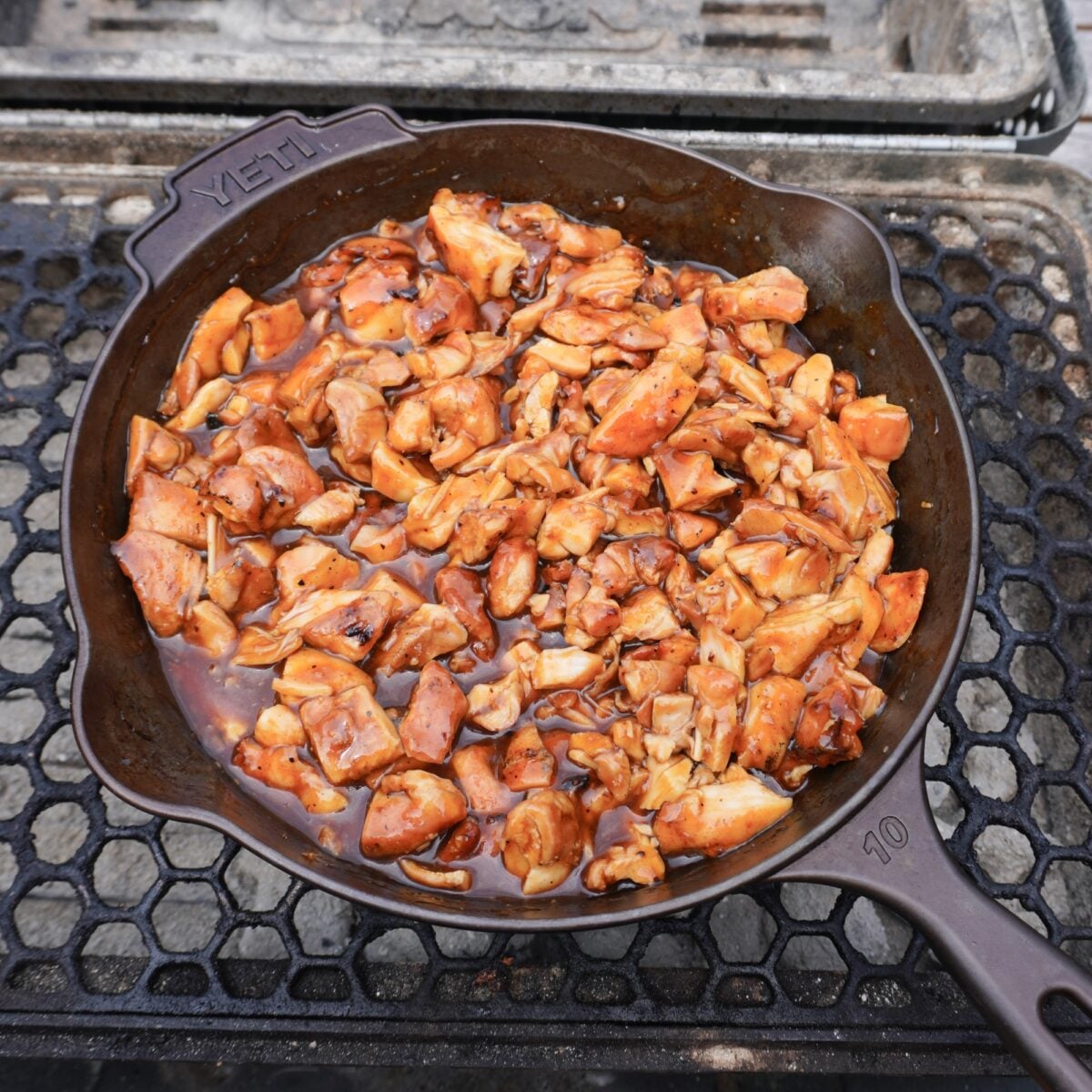 Grilled bourbon chicken dish in a cast iron skillet.