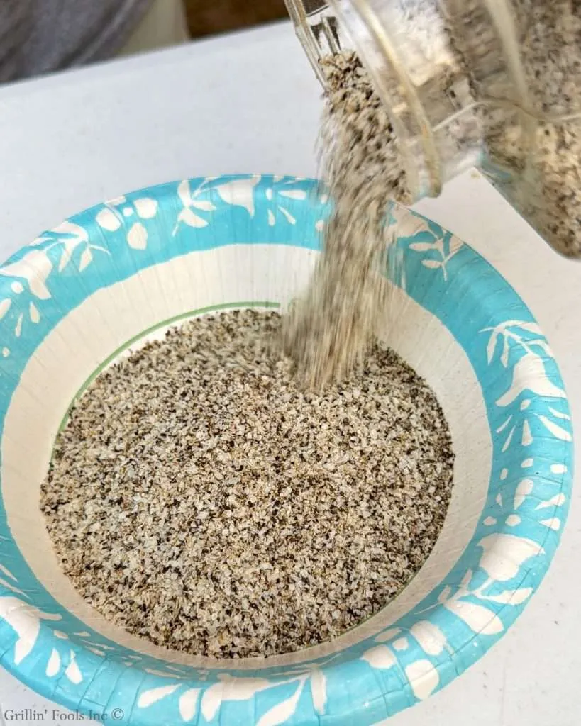 Salt pepper and garlic seasoning pouring into a paper bowl